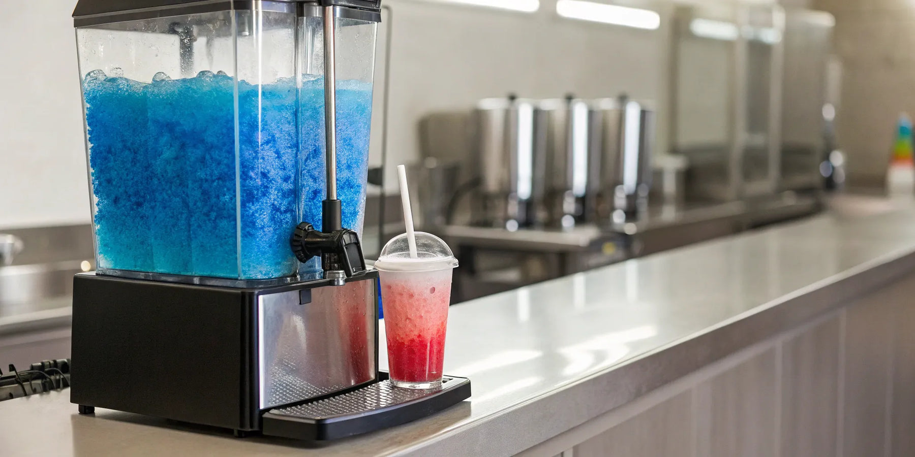 A commercial slushie machine with two flavors, red and blue, on a restaurant counter.