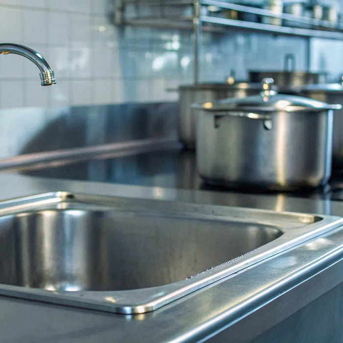A multi-bowl stainless steel commercial kitchen sink installed in a professional setting.