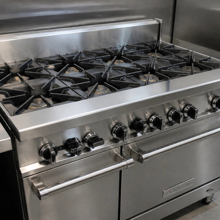 Line cook cleaning a commercial Atosa gas range cooktop with cast-iron grates removed and burner box exposed