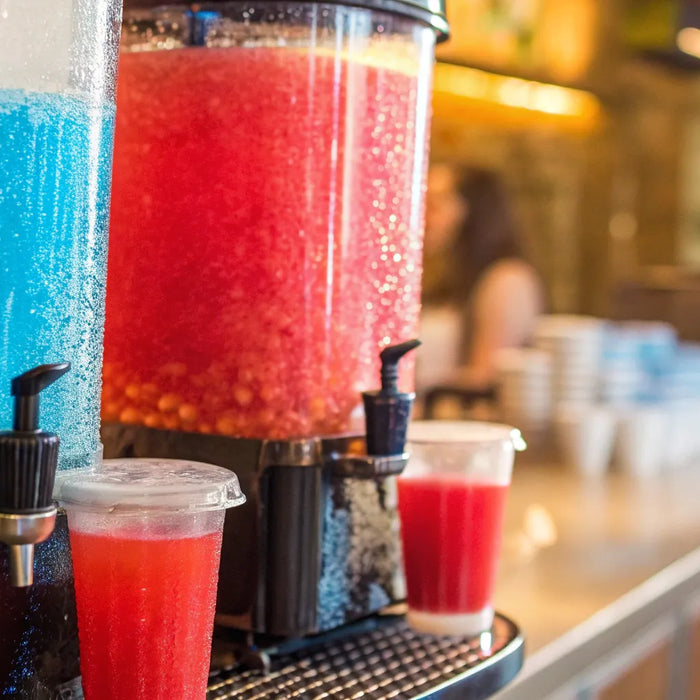 Red and blue slushie machines dispense frozen drinks.