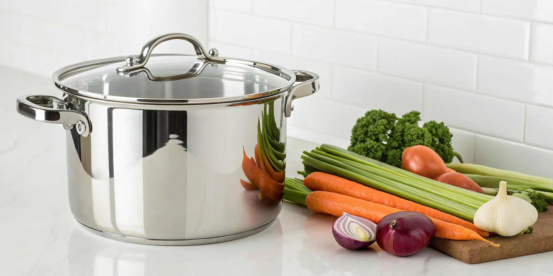 Stainless steel stockpot with vegetables on a counter.