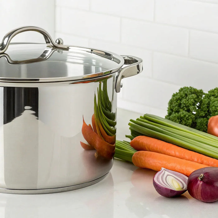 Stainless steel stockpot with vegetables on a counter.