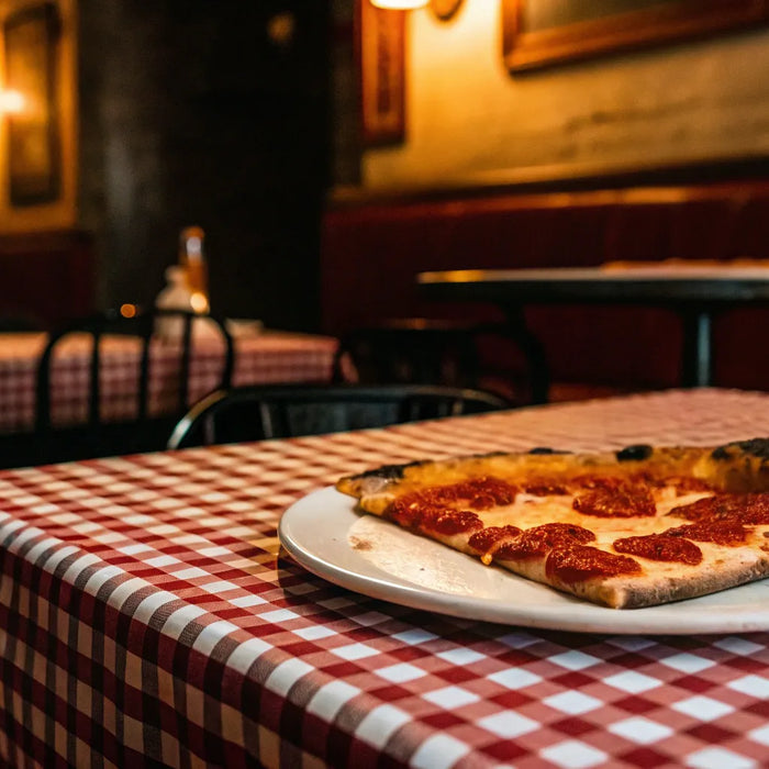 NYC pepperoni pizza slice on checkered tablecloth.