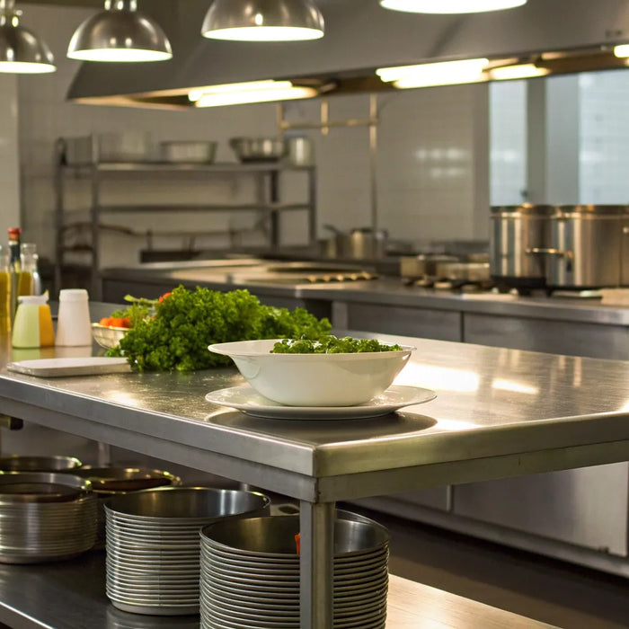 Stainless steel prep tables with undershelf storage in a commercial kitchen.