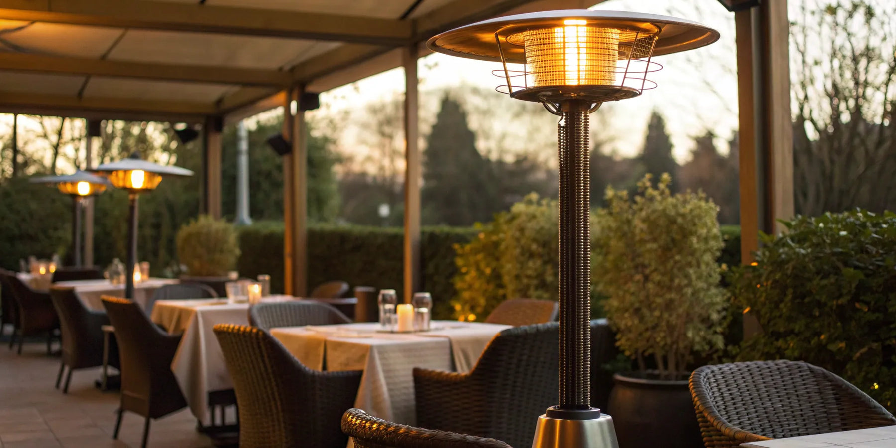 A commercial outdoor heater warming a restaurant patio with dining tables.