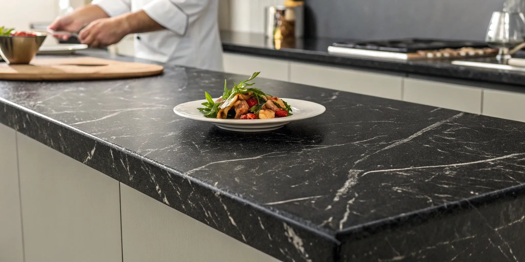 Chef plating a dish on a durable and veined black lava rock countertop.