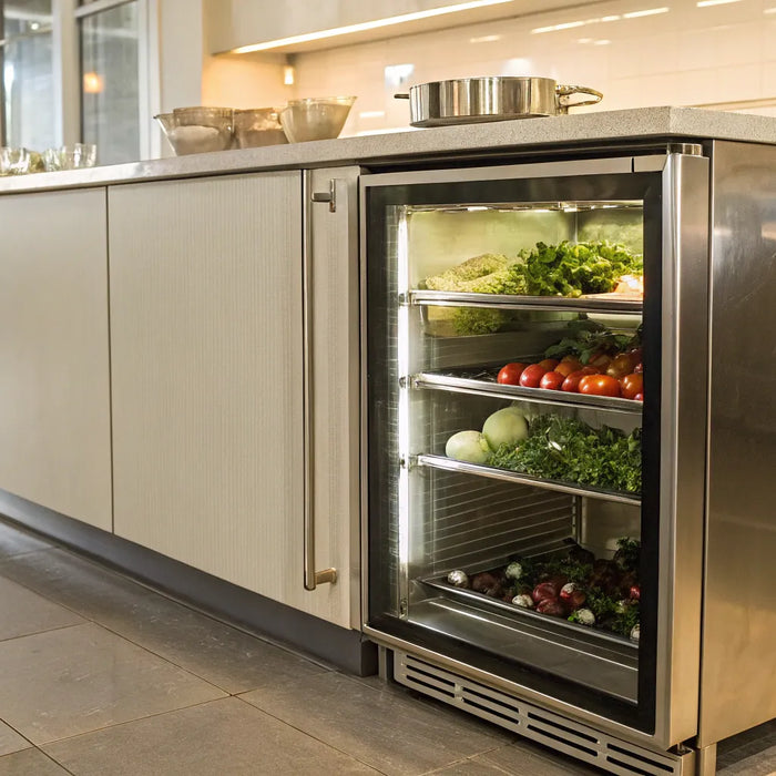 A stainless steel under counter cooler with a glass door in a commercial restaurant kitchen.