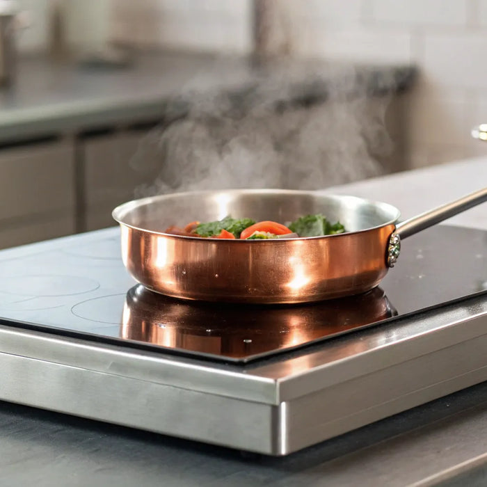 A commercial hot plate cooking food in a pan in a professional kitchen.