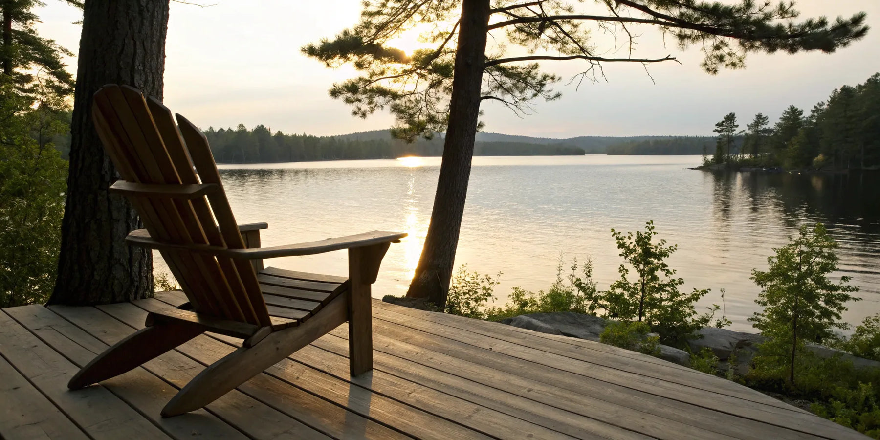 Adirondack chair on a porch overlooking a lake.