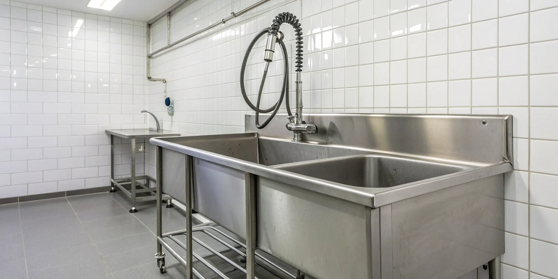 Stainless steel commercial mop sink with dual basins and a high backsplash.