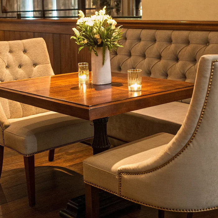 Coordinated commercial restaurant furniture with upholstered chairs, a wooden table, and banquette seating.