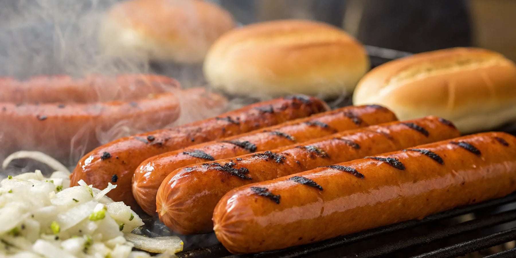 Hot dogs grilling on a hot dog grill.