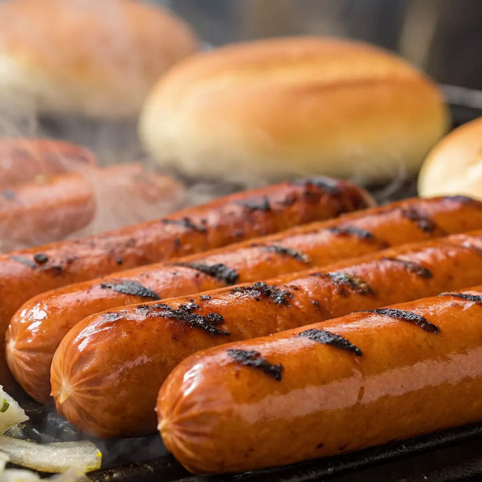 Hot dogs grilling on a hot dog grill.