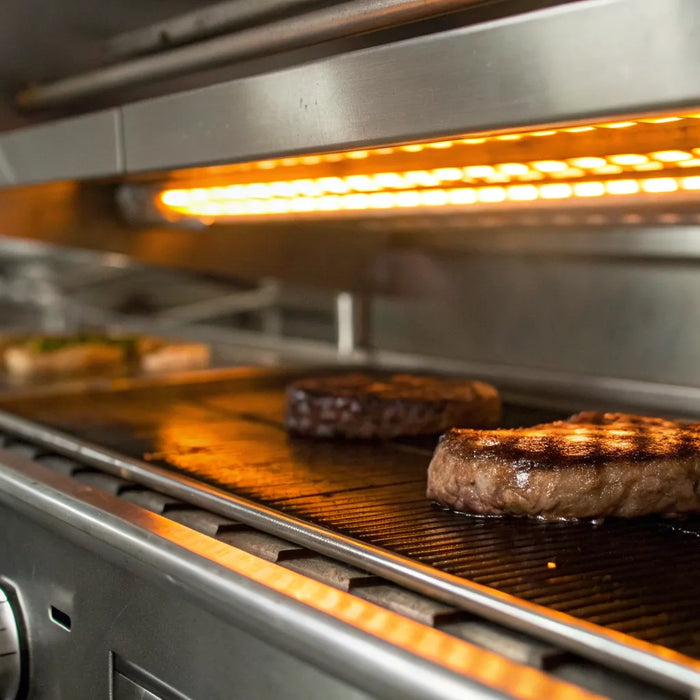 Salamander broiler searing steaks in a commercial kitchen.