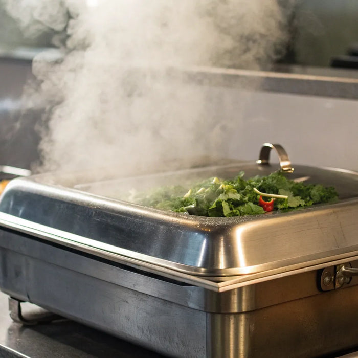 A commercial steam well uses steam to keep pans of food hot and ready for service.