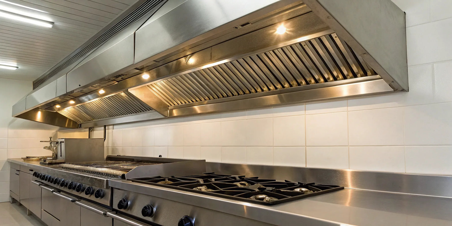Commercial kitchen hood with stainless baffle filters above cooking equipment